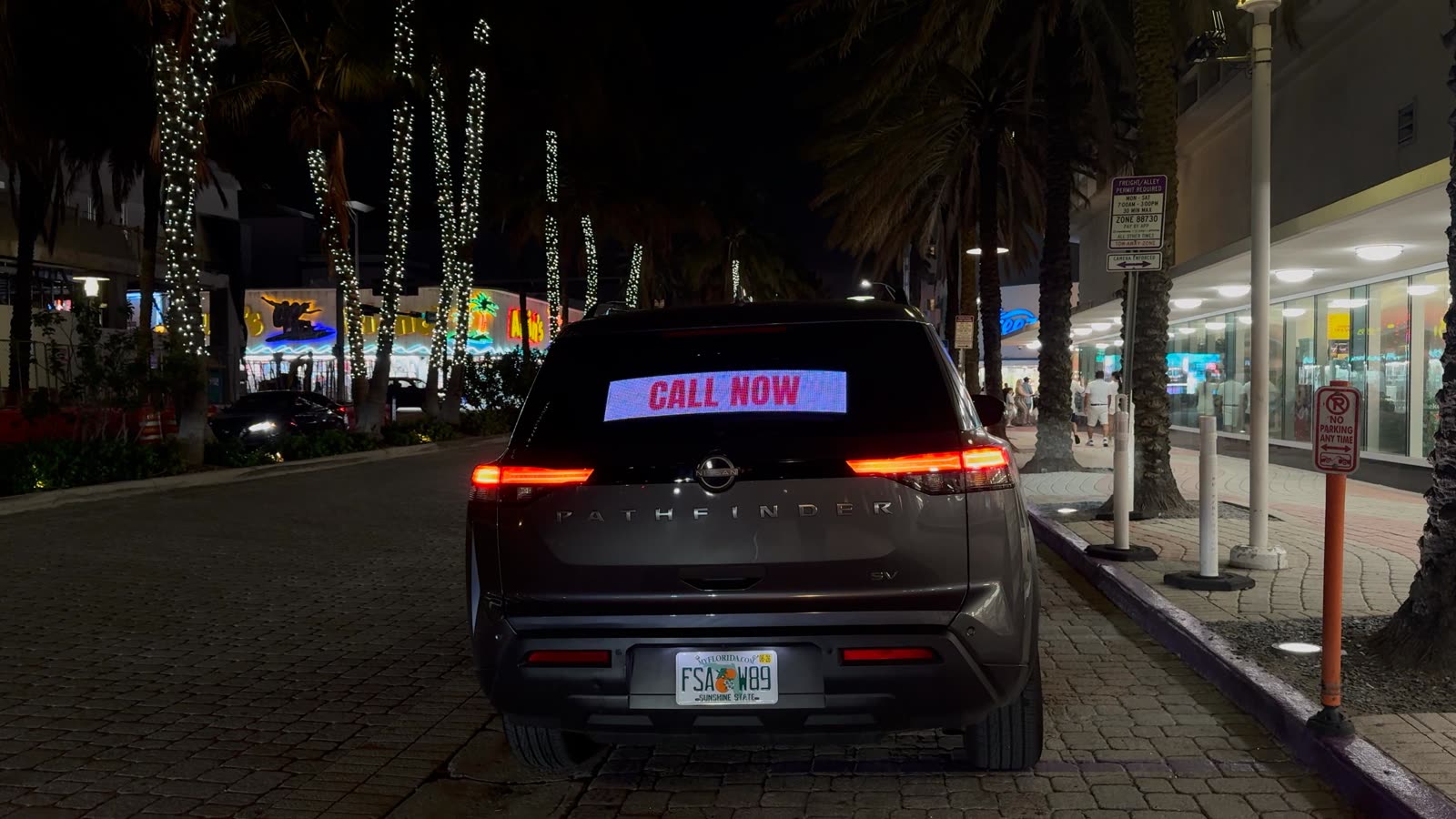 Mobill LED display on a car's rear window at night in Miami